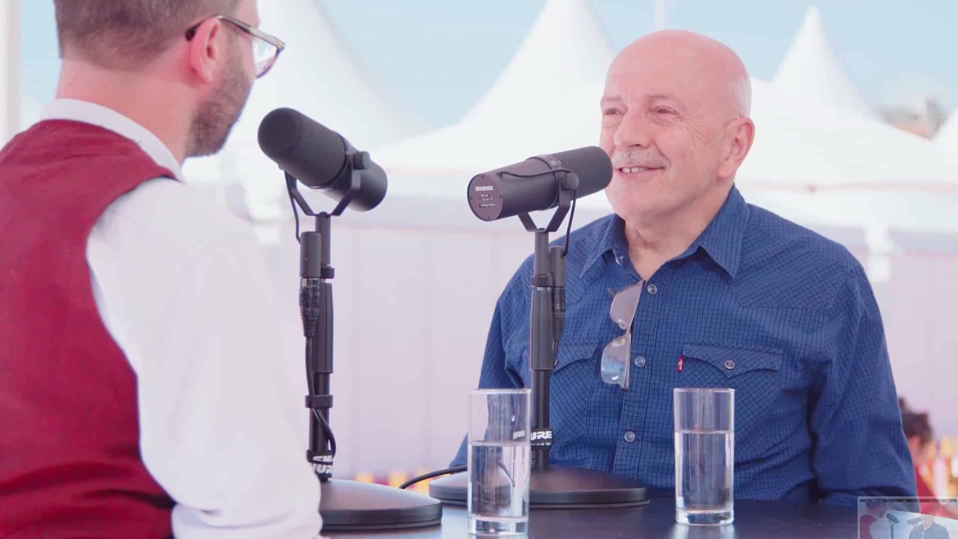 Jean Minondo assis devant un micro qui répond a une interview